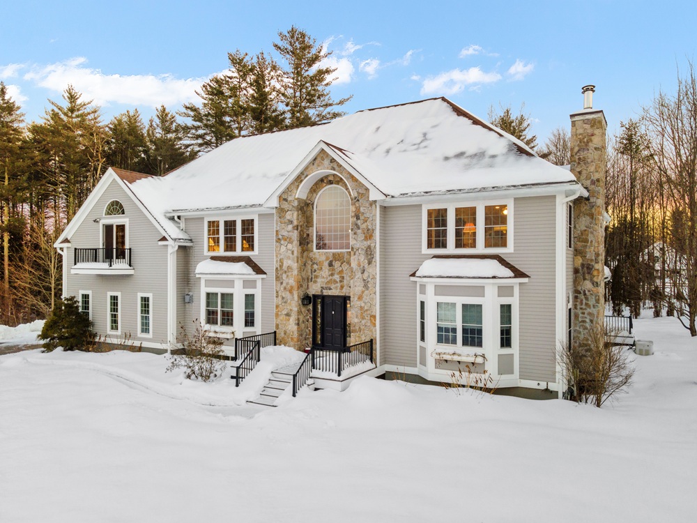 Modern two-story home in a snowy winter landscape with a stone chimney visible on the exterior